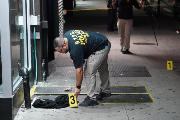 A member of the NYPD Crime Scene Unit places down an evidence marker at the scene Friday night.
